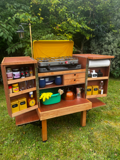 Wooden garden cart with shelves, containing tools, cans, and gardening supplies.