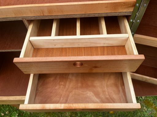 Open wooden drawer with dividers, showcasing a smooth interior.